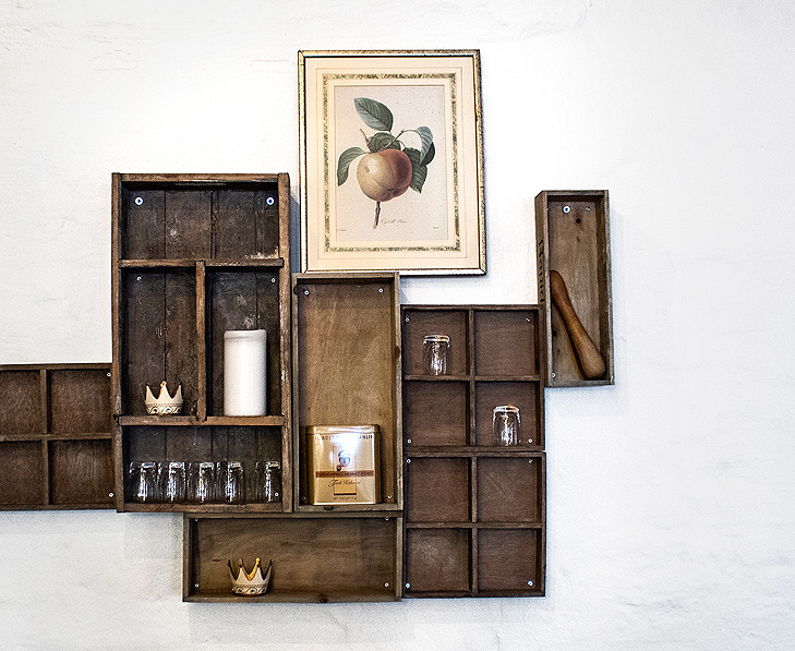 Interior decoration with shelving made of old wooden boxes. On the top of the shelves there is a frame with an old nature drawing of a peach.